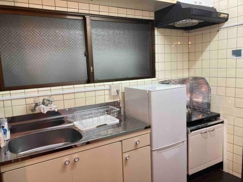 a kitchen with a sink and a refrigerator at 国際通りの宿 てぃーら in Makishimachi