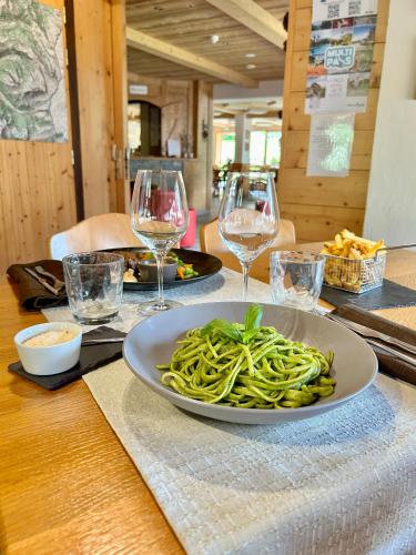 a plate of pasta on a table with wine glasses at Hameau des Prodains - Résidence in Morzine