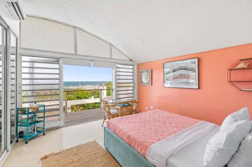 CeibaにあるOcean View w/ Huge Balcony @ Las Gaviotas Fajardo - Las Gaviotas A29 - Nuevoのオレンジ色の壁のベッドルーム、ベッド、バルコニーが備わります。