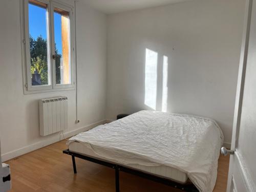 Bett in einem weißen Zimmer mit Fenster in der Unterkunft T3 Coeur de Pont de L'Arche in Pont-de-lʼArche