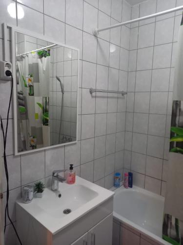 a white bathroom with a sink and a mirror at Apartman Sky in Bijeljina