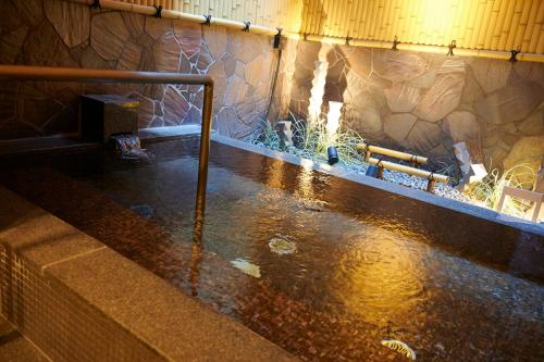 a pool of water in a room with a stone wall at Umekoji Potel KYOTO in Kyoto
