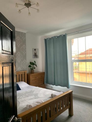 a bedroom with a bed with a blue curtain and a window at Stylish 91sqm Victoria 2 bedroom Apartment in Bristol