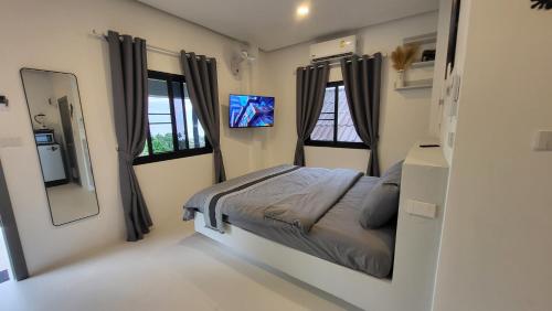a small bedroom with a bed and two windows at Moonway Bungalows in Koh Phangan