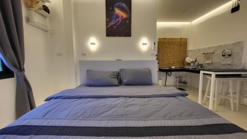 Schlafzimmer mit einem Bett mit blauen Kissen und einem Schreibtisch in der Unterkunft Moonway Bungalows in Ko Phangan