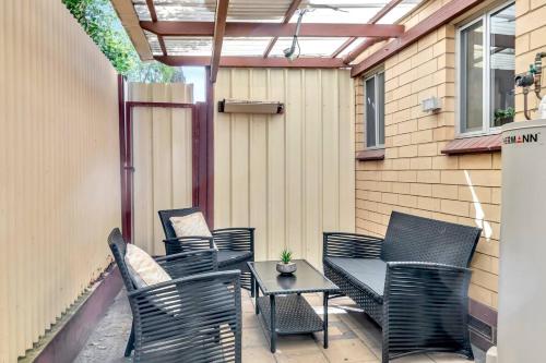 a patio with black chairs and a table and a building at Heart of Henley - A Homey Hideaway by the Beach in Adelaide