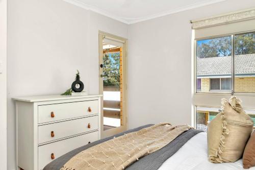 a bedroom with a bed with a dresser and a window at Heart of Henley - A Homey Hideaway by the Beach in Adelaide