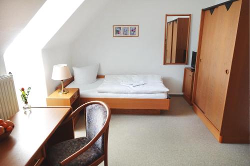 a small room with a bed and a table and chairs at Pension Zur Inselbrücke in Wolgast