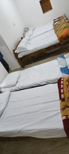a group of white beds in a room at Raagabynature home stay in Gendehalli