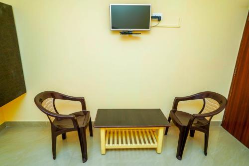 two chairs and a table and a tv on a wall at Ssunshhine residency (NEW) in Tirupati