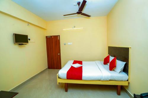 Schlafzimmer mit einem Bett mit roten und weißen Kissen in der Unterkunft Ssunshhine residency (NEW) in Tirupati