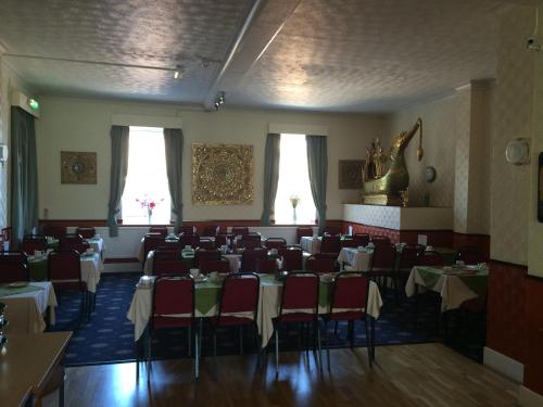 a dining room with tables and chairs and two windows at Hotel Victoria in Great Yarmouth