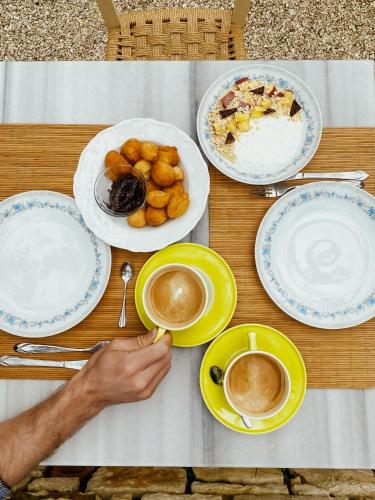 a table with plates of food and cups of coffee at ELÉA Guesthouse himare in Himare
