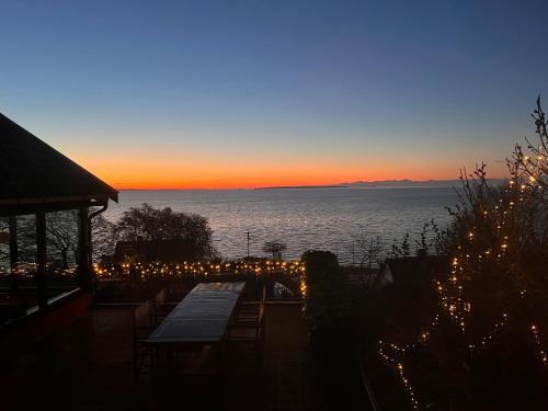 a view of the sunset from a patio with lights at Sea view nordic design apartment near beach great for couples in Snekkersten