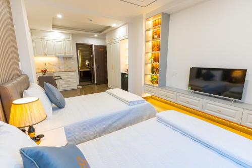 a bedroom with two beds and a flat screen tv at CM Hotel & Apartment in Hai Phong
