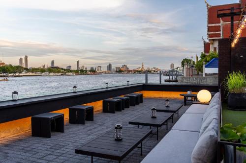 eine Reihe von Tischen auf einer Terrasse neben dem Wasser in der Unterkunft Theatre Residence in Bangkok