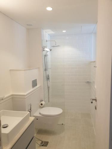 a white bathroom with a toilet and a shower at Golf Lake Penthouse in As Sīfah