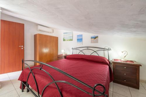 1 dormitorio con cama roja y armario de madera en Il Lentischio - Rosmarino, en SantʼAntìoco
