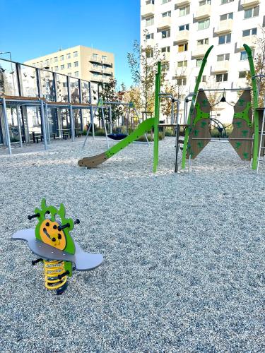 a playground with a toy in front of two swings at Apartmán s klimatizáciou a balkónom pri letisku BTS in Bratislava