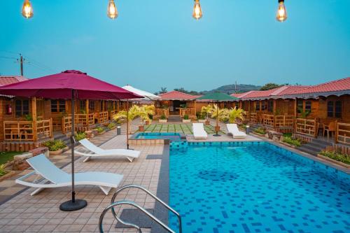 a pool at a resort with chairs and umbrellas at Grace Exotica Goa in Canaguinim