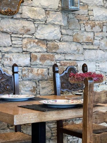 a wooden table with two chairs and a stone wall at ELÉA Guesthouse himare in Himare