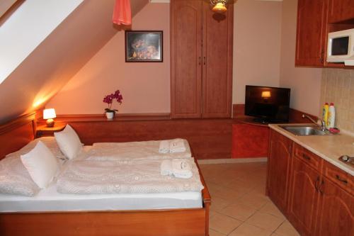 1 dormitorio con 1 cama y cocina con fregadero en Rozmann Family Panzió & Apartmanhaz, en Sárvár