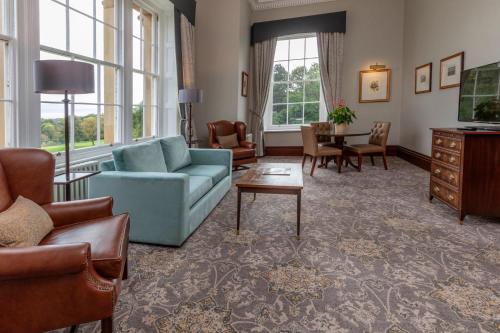 a living room with a blue couch and a table at Oulton Hall Hotel, Spa & Golf Resort in Leeds