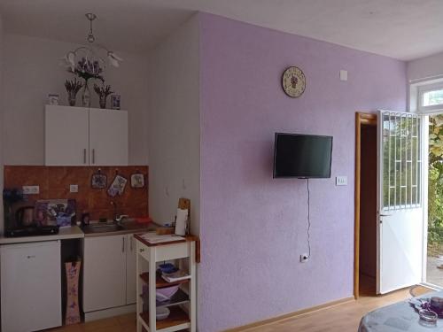 a kitchen with a purple wall with a tv on the wall at Apartman Lavanda in Trebinje