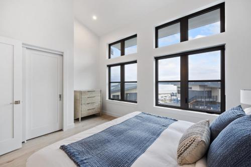 a bedroom with white walls and large windows at Coastal Haven at THE BEACH HOUSE in Campbell River