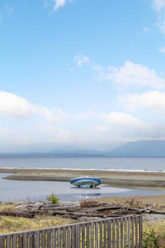 a boat sitting in the water next to a fence at Coastal Haven at THE BEACH HOUSE in Campbell River