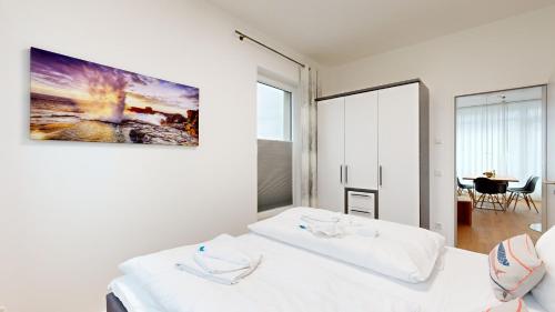 a white room with two beds and a table at DünenResort in Binz, strandnahe und moderne FeWos mit Balkon, teilweise mit Meerblick, in Binz