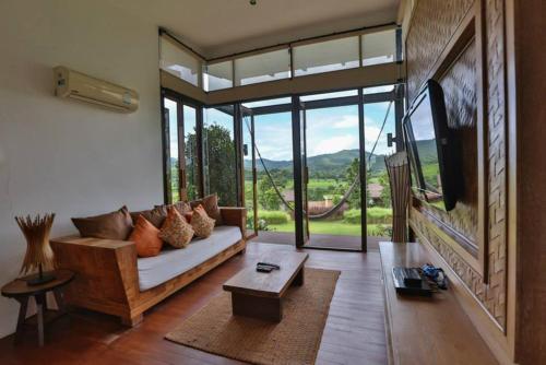 a living room with a couch and a large window at Puripai Villa in Pai