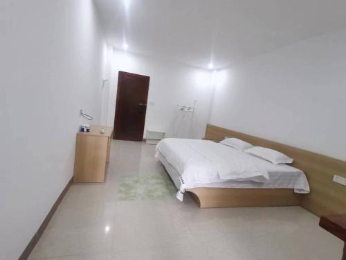a bedroom with a white bed and a brown door at Olioinn B&B in Wenchang