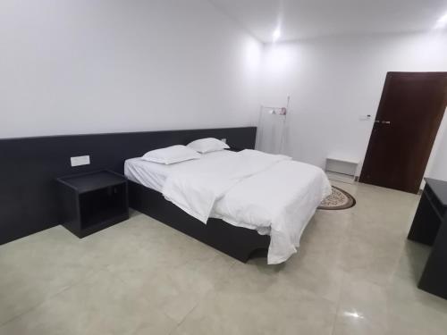 1 dormitorio con 1 cama con sábanas y almohadas blancas en Olioinn B&B, en Wenchang