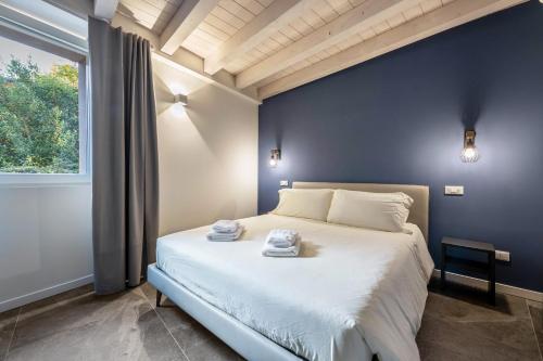 1 dormitorio con 1 cama grande y pared azul en La Casa Incartata - Carta da Zucchero, en Toscolano Maderno