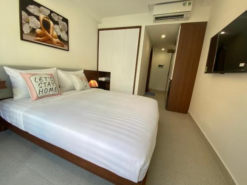 een slaapkamer met een groot wit bed en een televisie bij Saigon Hotel & Apartment in Ho Chi Minh-stad