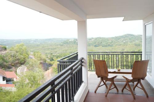 a balcony with two chairs and a table with a view at Vaidekam Resorts & Wellness, Kannur in Kannur