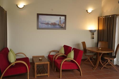 a waiting room with red chairs and a table at Vaidekam Resorts & Wellness, Kannur in Kannur