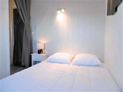 a bedroom with a white bed with two pillows at Maisonnette 5 pièces 6 personnes avec WIFI - JUNA in Sarzeau