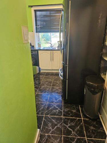 a kitchen with a black refrigerator and a tile floor at The Margaret Residence in Bexhill