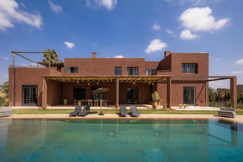 a house with a swimming pool in front of a house at Fellah Hotel in Marrakesh