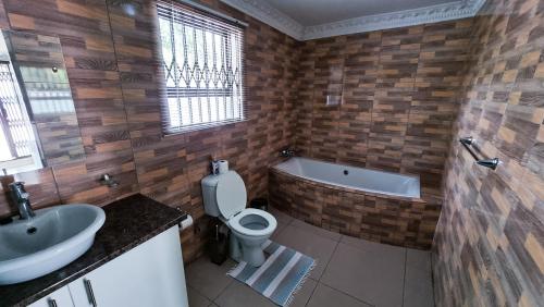 a bathroom with a toilet and a sink and a tub at Gracious Lodge in Burgersfort