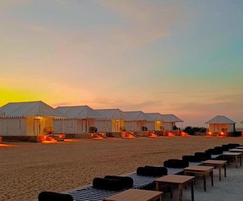 a row of tents on the beach at sunset at Desert Safari Camp & Resort Sam in Sām