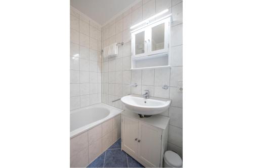 a white bathroom with a sink and a bath tub at Ferienwohnung Königsleiten 25 - Top 44 in Königsleiten