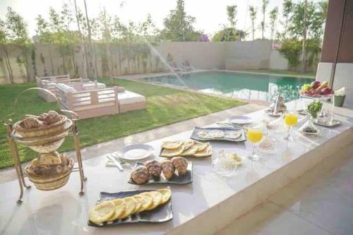 - une table avec de la nourriture et des boissons près de la piscine dans l'établissement Eden Villa, à Marrakech