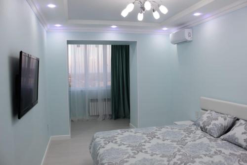 - une chambre blanche avec un lit et une télévision dans l'établissement Двухкомнатная квартира в центре города, à Uralsk