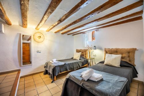 two beds in a room with wooden ceilings at New! Villa Na Ribes in Sant Carles de Peralta