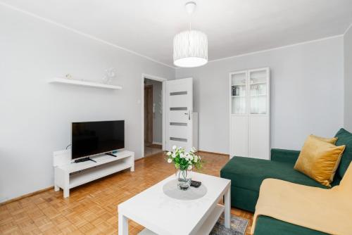 a living room with a green couch and a tv at Apartment Floriana Stablewskiego Poznań by Renters in Poznań