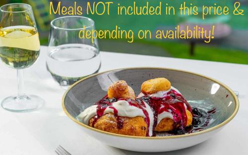 a bowl of food on a table with a glass of wine at English Home in Silver Mountain Resort Poiana Brasov in Poiana Brasov