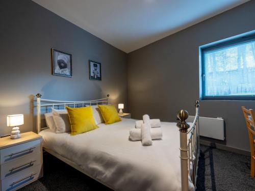 Un dormitorio con una cama con almohadas amarillas y una ventana en Pass the Keys Modern flat a short walk from Shrewsbury centre, en Shrewsbury